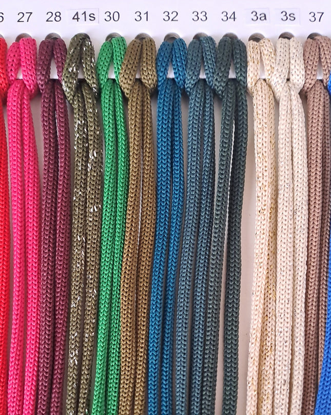 Color chart of polyester cords for macramé and crochet, featuring a variety of shades numbered from 25 to 38, including red, pink, burgundy, glitter olive, green, gold, teal, beige, cream, blue, and yellow.